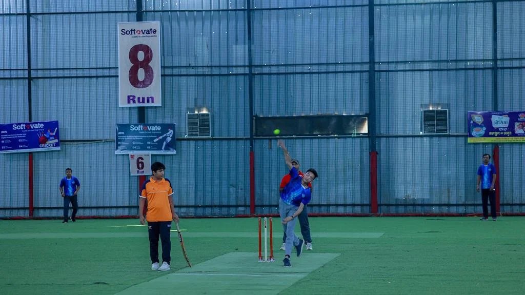 Indoor cricket match at the JSG Legends LPL tournament with Softovate co-sponsor branding on the field